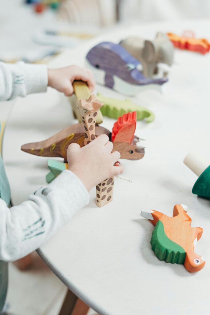 A young child creatively plays with colorful wooden toys on a table, fostering imagination and learning.