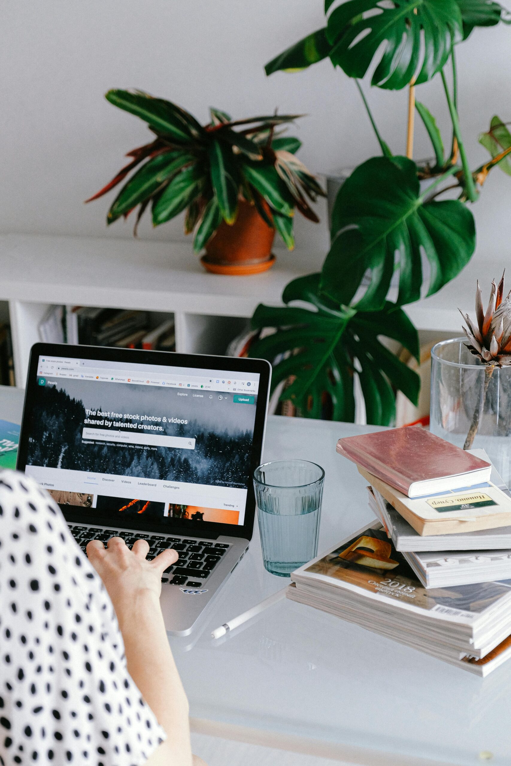 A woman working from home on her laptop surrounded by plants and books for a cozy office feel.